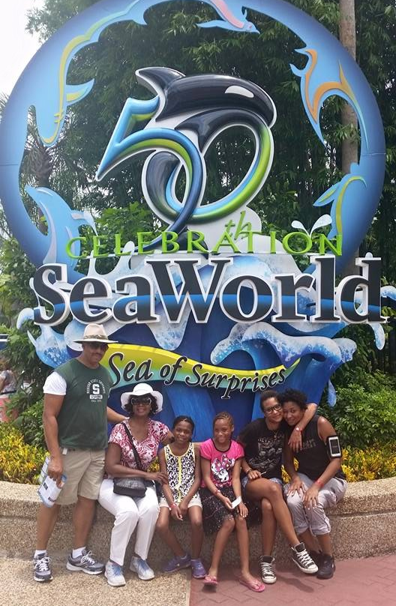 annie eure with husband and children at Sea World in Florida. annie eure is wearing white pants and a white hat.